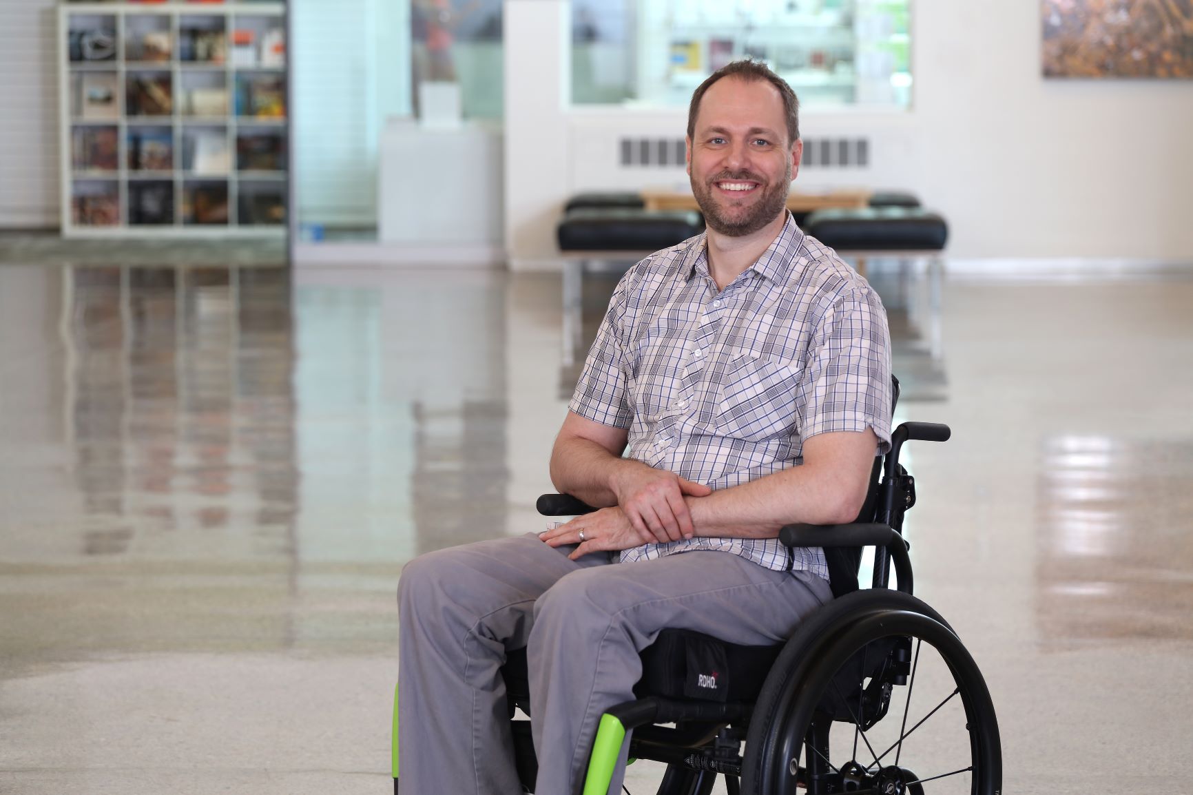 Andrew Ashby is smiling. He sits in his wheelchair in a bright, open room.